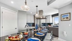 Une cuisine moderne dotée d’un grand îlot central, d’appareils électroménagers en acier inoxydable et d’une grande fenêtre.