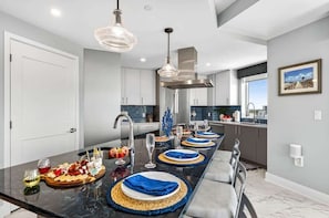 A modern kitchen with a long island, stainless steel appliances, and a large window. - Pura Vida in Clearwater Beach (Clearwater Beach)