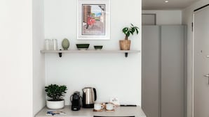 A modern kitchen with a white countertop, a coffee maker, two cups, a kettle, and a WiFi sign. - Batèl House 1 - By Breva Collections (Como)