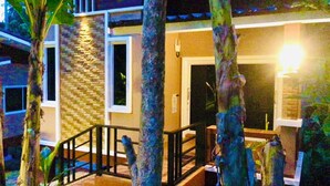 A building with a stone facade, a wooden deck, and a black railing. - Lucky Sky Homestay (Ko Pha-ngan)