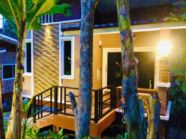 A building with a stone facade, a wooden deck, and a black railing. - Lucky Sky Homestay (Ko Pha-ngan)