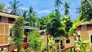 A residential area with multiple two-story houses, surrounded by lush greenery and palm trees.