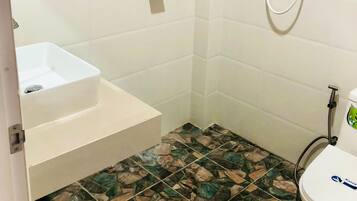 A bathroom with a white sink, a shower, and a toilet.