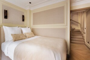 A hotel room with a bed, a staircase, and a wall with a textured panel. - Merveil Luxury Suite - Louvre - Dalayrac (Paris)