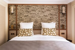 A hotel room with a large bed, two pillows, a headboard with a textured wall, and wall sconces. - Merveil Luxury Suite - Louvre - Dalayrac (Paris)