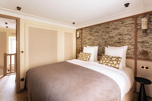 A bedroom with a large bed, a wooden door, and a textured wall. - Merveil Luxury Suite - Louvre - Dalayrac (Paris)