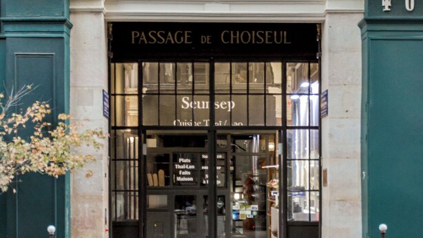 Der Eingang zum Passage de Choiseul, ein historisches Gebäude mit einer klassischen Fassade und Rundbogenfenstern.