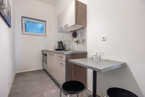 A compact kitchen with a window, a sink, a stove, and a small dining table. - Apartment 'Altenbeken- 1' with Wi-Fi (Altenbeken)