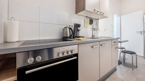 A modern kitchen with a built-in oven, a coffee maker, and a hanging rack.