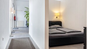 A narrow hallway with a bed, a wall-mounted light, and a plant.
