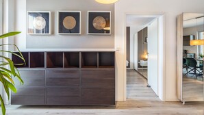 A modern interior with a wooden floor, a large dark wooden cabinet, and framed wall art. - Apartment 'Altenbeken-2' with Private Terrace, Private Garden and Wi-Fi (Altenbeken)