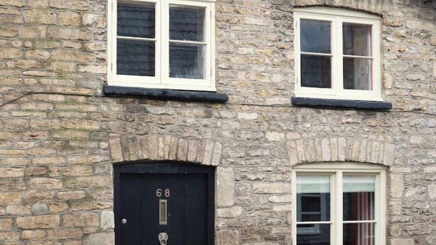 A stone building with two windows and a black door with the number 68. - Townhouse by The Old Bell Hotel -68 Abbey Row (Malmesbury)