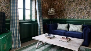 A room with a blue sofa, a white coffee table, and patterned wallpaper. - Townhouse by The Old Bell Hotel -68 Abbey Row (Malmesbury)