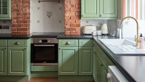 A kitchen with green cabinets, a brick wall, a toaster, and a sink. - Townhouse by The Old Bell Hotel -68 Abbey Row (Malmesbury)