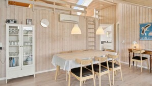 A room with a wooden interior, a dining table with chairs, a cabinet with glass doors, and a ladder against the wall.