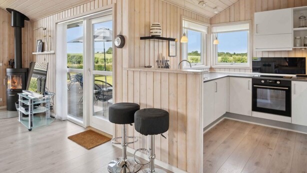 A modern kitchen with wooden paneling, a large window, and a built-in oven.