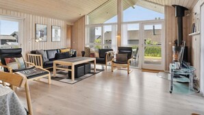 A spacious living area with a wooden ceiling, large windows, and a fireplace.