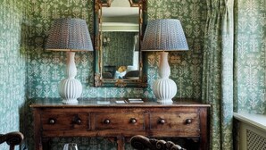 A vintage-style room with a wooden dresser, two patterned lamps, and a mirror above it.