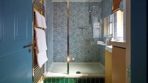 A bathroom with a shower, a sink, and a window.