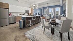 A modern kitchen with a central island, bar stools, and a dining table with chairs.