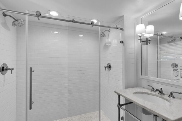 Une salle de bain moderne avec une douche à parois de verre, un lavabo en marbre et un grand miroir.