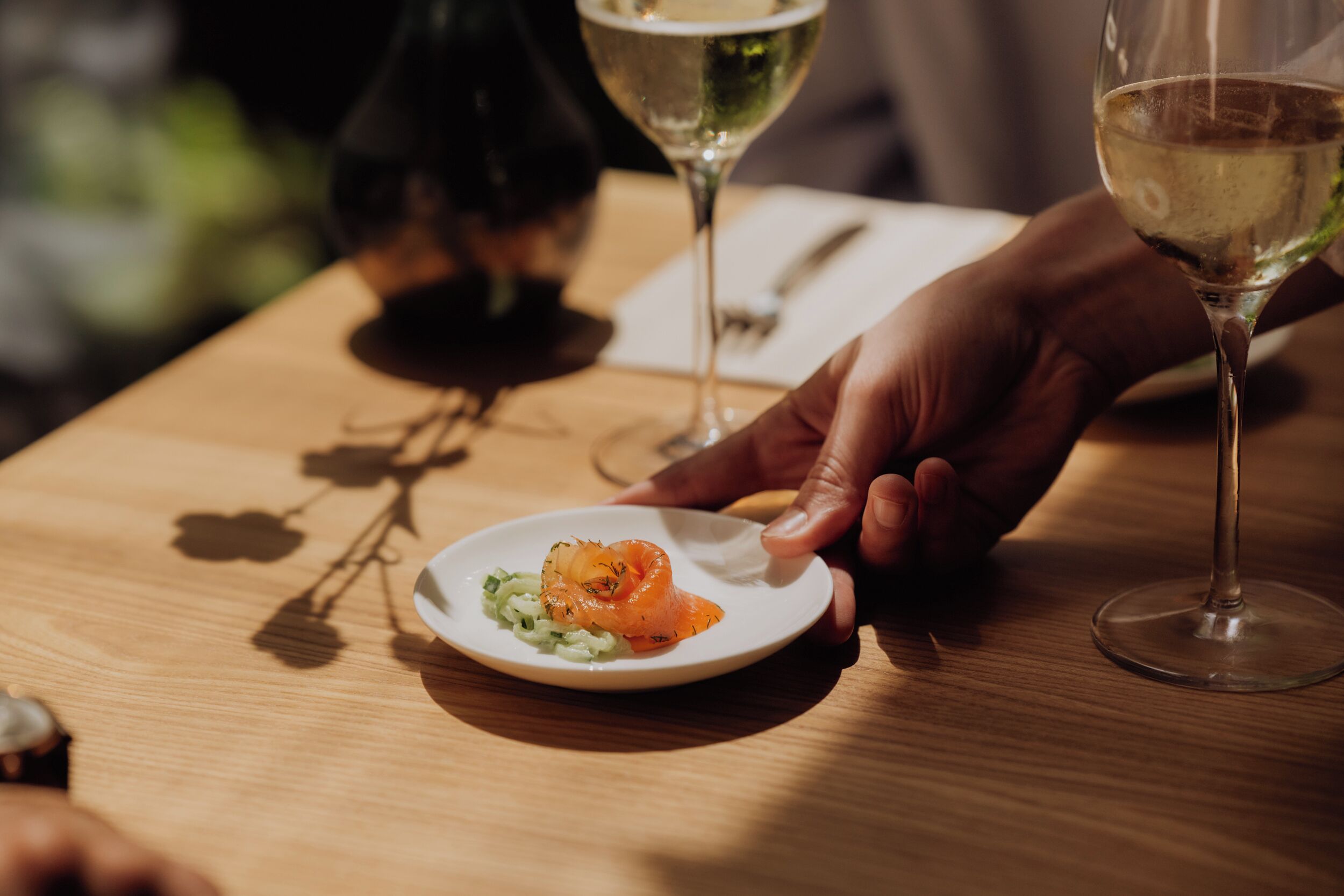 Una mesa de comedor con un plato de comida, una copa de vino y una botella.