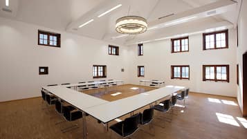 Una amplia sala de conferencias con una larga mesa, múltiples sillas y grandes ventanales que dejan entrar luz natural.