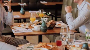 A dining table with breakfast items, including croissants, coffee, and juice.