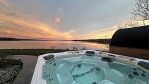 Ein Whirlpool mit Blick auf einen See und einen Sonnenuntergang.