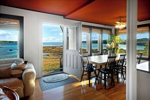 Un coin repas avec vue sur la mer, un canapé et une table avec des chaises.