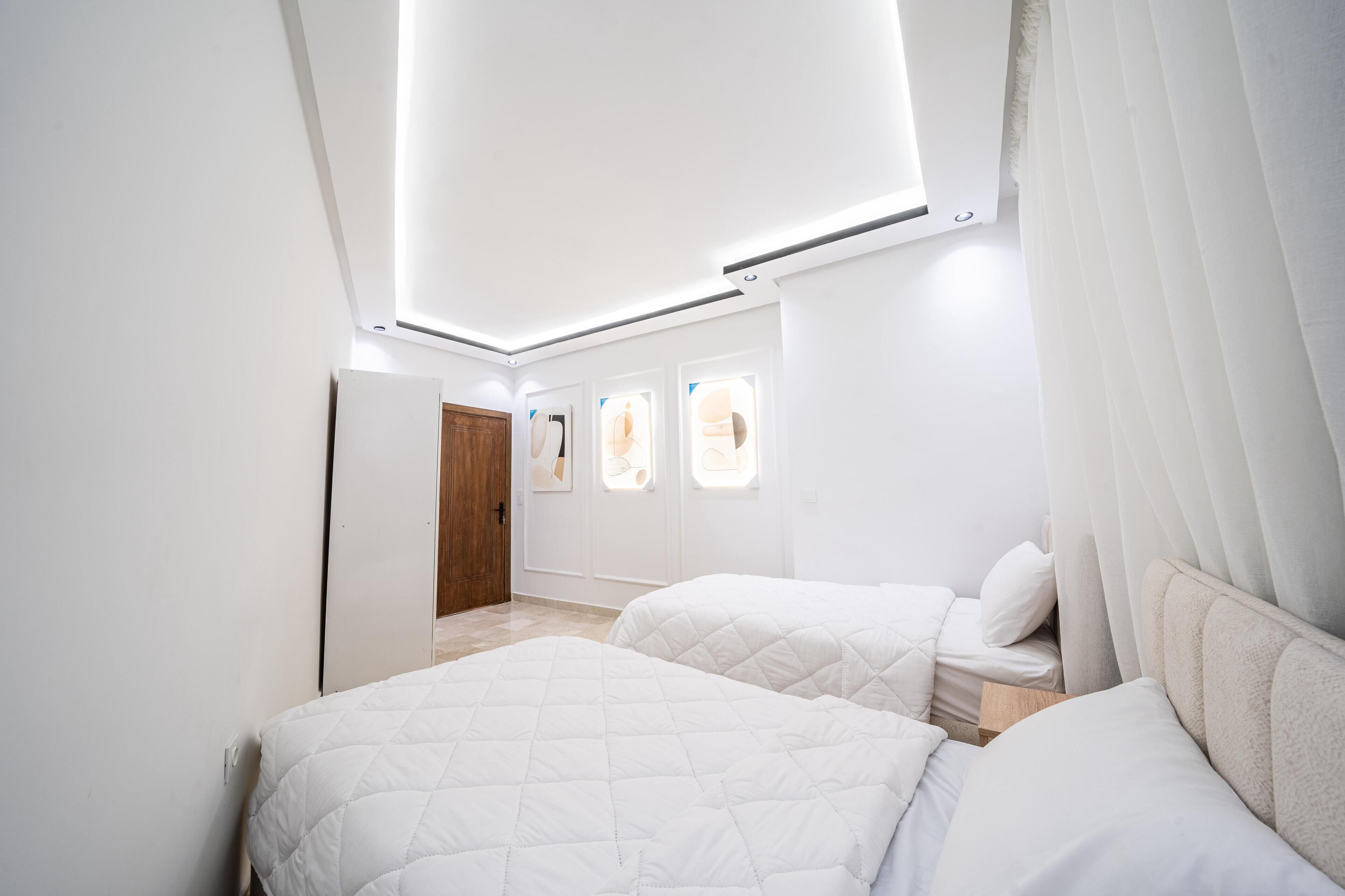 Ein Schlafzimmer mit zwei Betten, einer Holztür und einem Fenster mit Blick nach draußen.