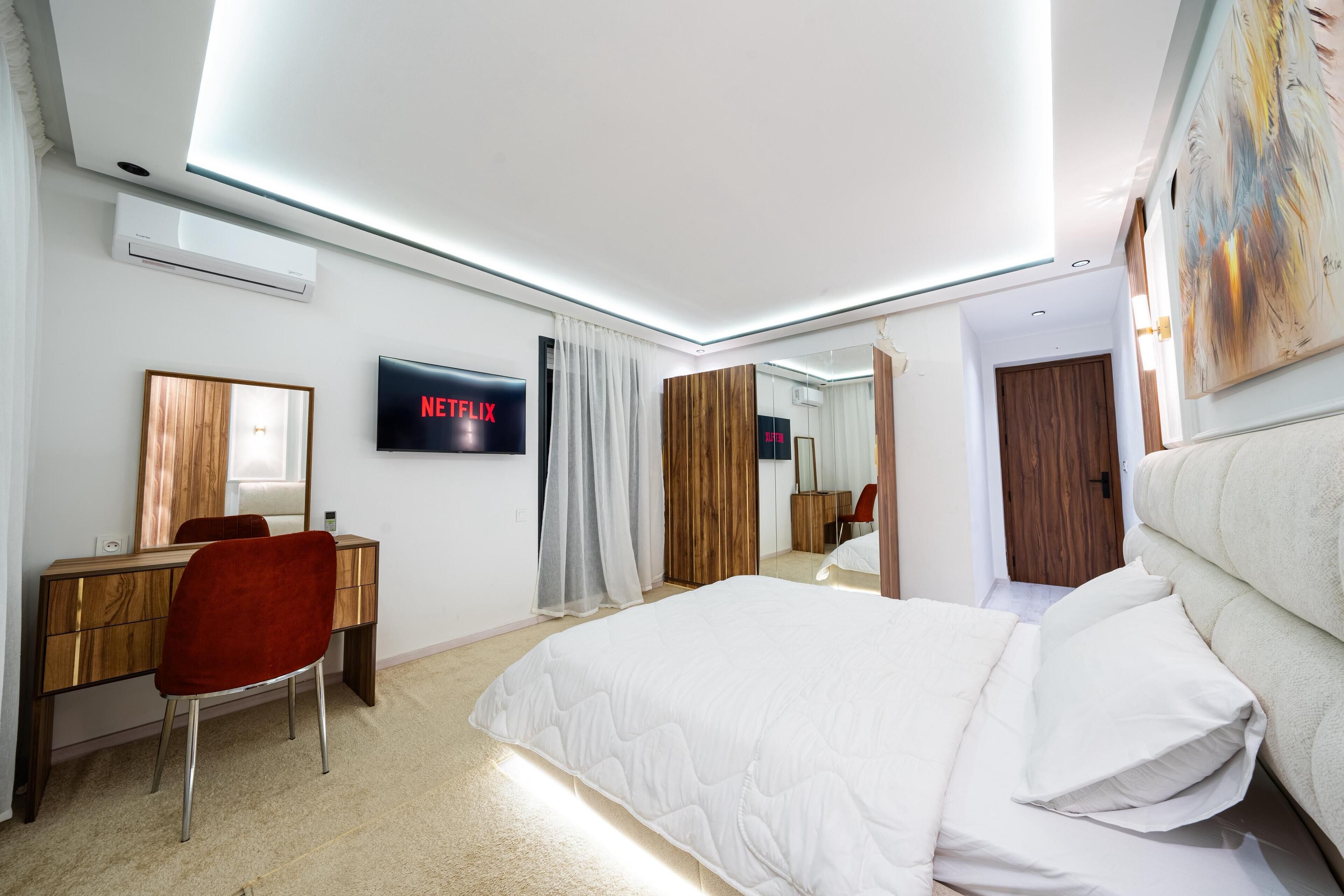 Camera d'albergo moderna con un letto, una scrivania, una sedia, una TV e un grande specchio.