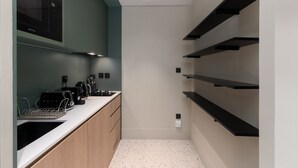 A modern kitchen with a built-in microwave, toaster, and coffee maker on the counter. There are wooden cabinets and a white countertop. - Burj View Studio Near Downtown and Canal (Dubai)