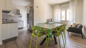 A modern kitchen with a dining area, featuring a table with chairs, a sofa, and a window with curtains. - Appartamento Pacini by Wonderful Italy (Palermo)