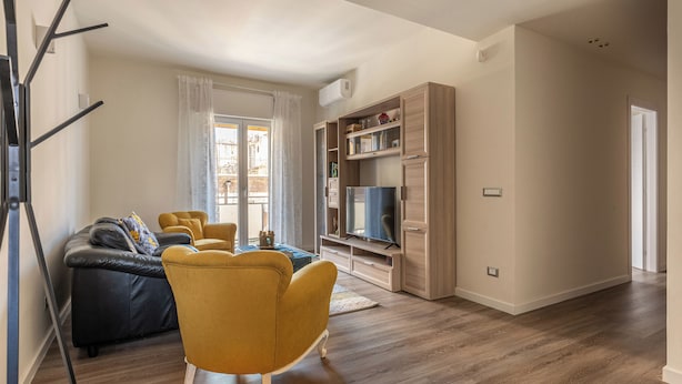 A modern living room with a sofa, yellow armchair, and entertainment unit. - Appartamento Pacini by Wonderful Italy (Palermo)