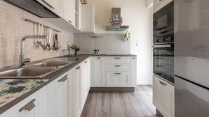 A modern kitchen with white cabinetry, stainless steel appliances, and a patterned backsplash. - Appartamento Pacini by Wonderful Italy (Palermo)