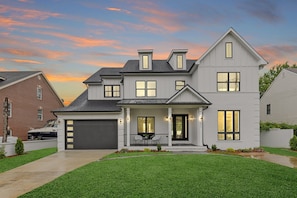 A two-story house with a front porch, a garage, and a well-maintained lawn. - Stunning 6-bedroom house in Falls Church-Luxury Awaits! (Falls Church)