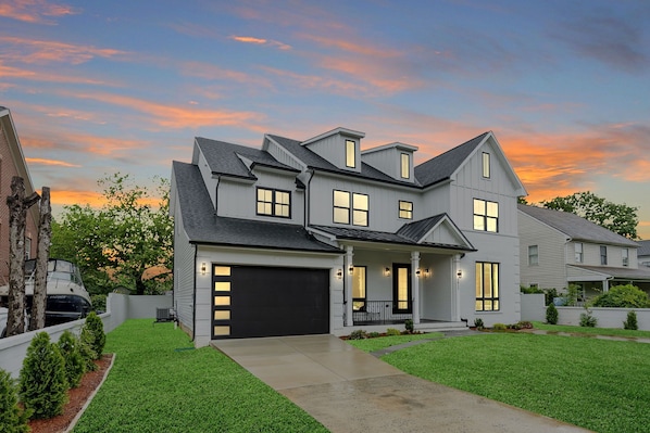 A two-story house with a garage, a covered porch, and a well-maintained lawn. - Stunning 6-bedroom house in Falls Church-Luxury Awaits! (Falls Church)