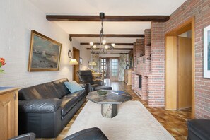 A living room with a leather sofa, a stone coffee table, a fireplace, and a dining area in the background.