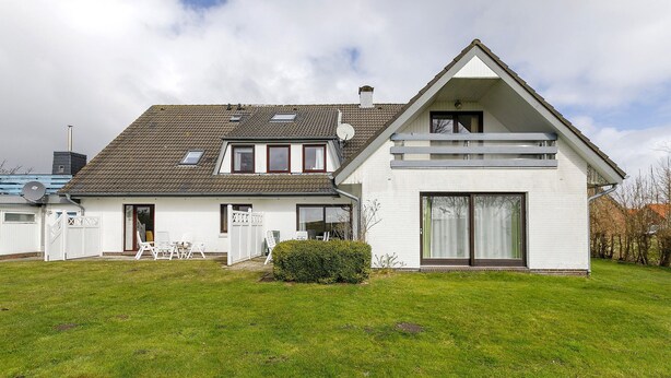 A two-story house with a sloped roof, large windows, and a well-maintained lawn. - Apartment 'Fewo 3 Gröde' with Shared Terrace, Shared Garden and Wi-Fi (Dagebüll)