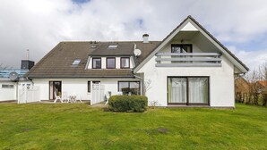 A two-story house with a sloped roof, large windows, and a well-maintained lawn. - Apartment 'Fewo 5 Hamburger Hallig' with Shared Terrace, Shared Garden and Wi-Fi (Dagebüll)