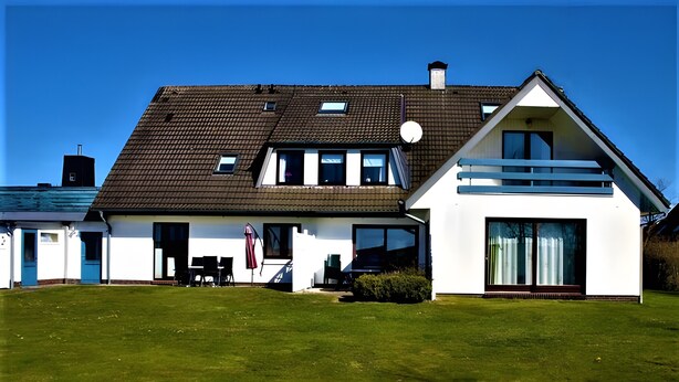 A modern two-story house with a sloped roof, large windows, and a well-maintained lawn. - Apartment 'Fewo 5 Hamburger Hallig' with Shared Terrace, Shared Garden and Wi-Fi (Dagebüll)