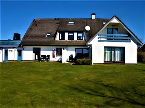 Une maison moderne à deux étages, dotée d’un toit en pente, de grandes fenêtres et d’une pelouse bien entretenue.