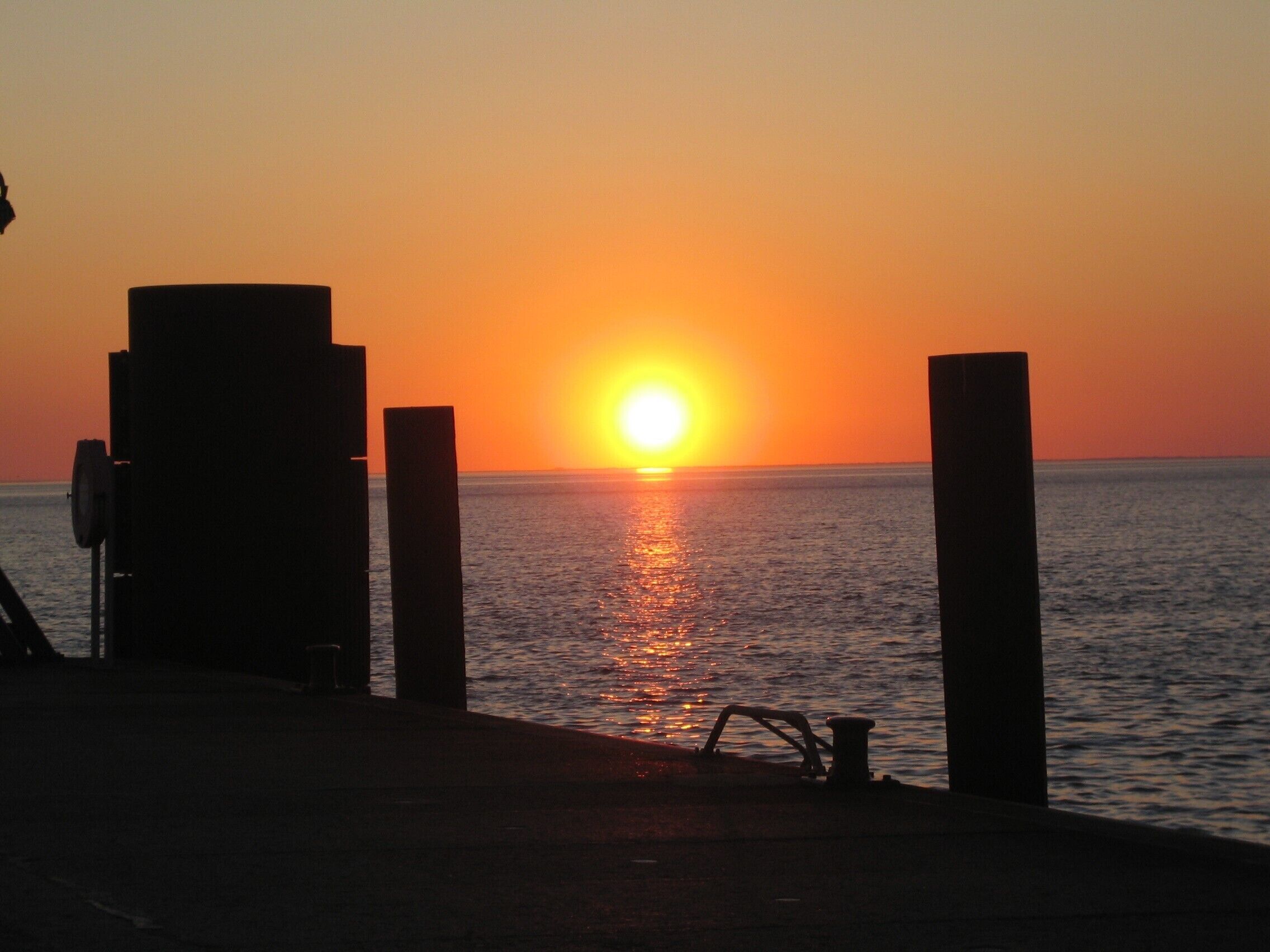 A sunset over the ocean with a pier extending into the water.