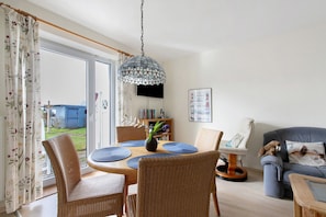 Un espace repas comprenant une table ronde, des chaises et un luminaire suspendu.