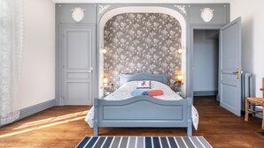 A bedroom with a bed, a nightstand, a lamp, a dresser, and a door. - Dentelles Guest Room (Neuvic)