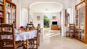 A spacious room with a dining table, chairs, a television, and bookshelves. - Dentelles Guest Room (Neuvic)