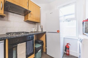 A compact kitchen with a gas stove, oven, and a white refrigerator.