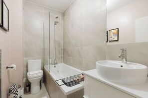 A modern bathroom with a toilet, a shower, and a sink. - Chic 1BD Flat in Restored English Pub, East London (Greater London)