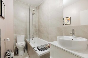 Een badkamer met toilet, bad en wastafel.